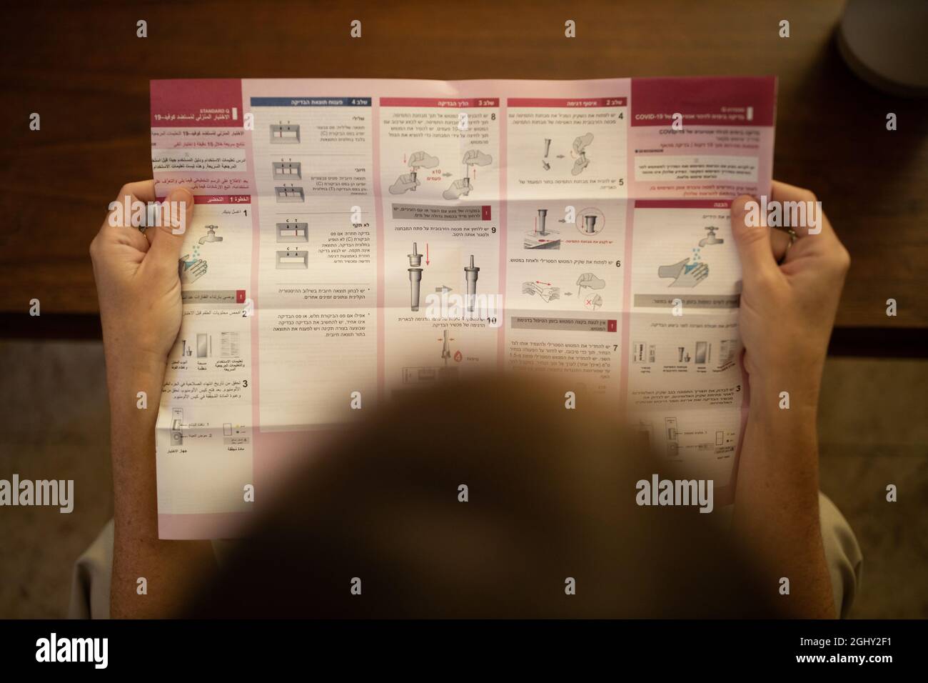 Frau liest Anweisungen, bevor sie zu Hause einen Covid-19-Selbsttest durchführt Stockfoto