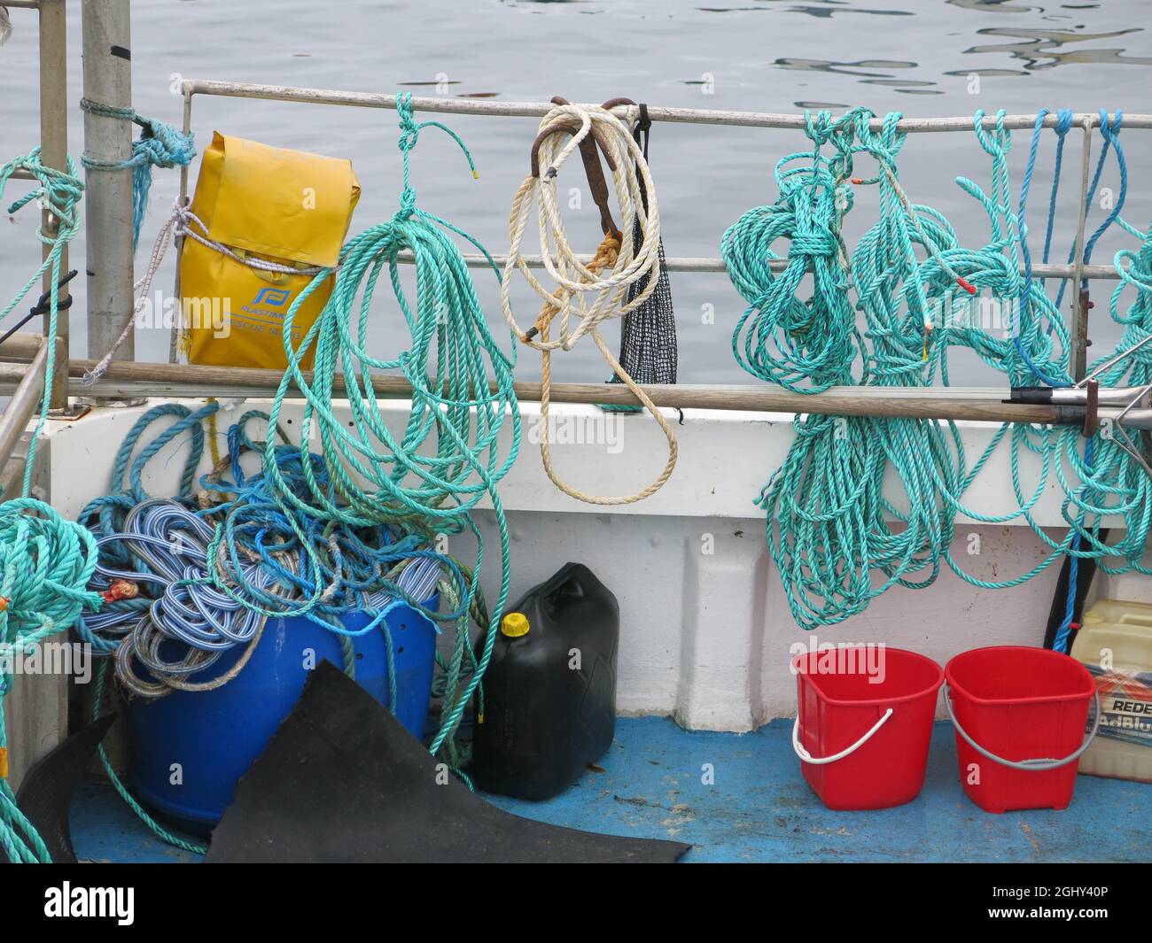 Farbenfrohe Nahaufnahme der Seile, zwei rote Eimer und Tackle an Bord eines Fischerbootes im Hafen von Mallaig an der Westküste Schottlands. Stockfoto