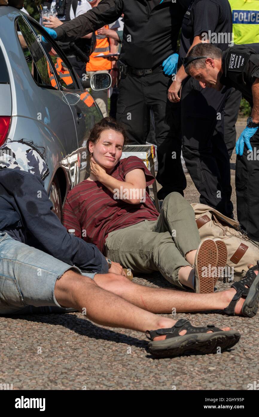 London, Großbritannien. September 2021. Eine Protestierende zieht ihre Sonnencreme an, während sie gegen die Waffenmesse demonstriert, während die Polizei sie auszieht, da sie sich in und um ein Auto auf der A1020 geklebt und den Zugang zu dem für die DSEI (Defence and Security Equipment International) in Excel London aufgestellten Fahrzeug blockiert haben. Die vom 14. Bis 17. September stattfinden soll. Kredit: SOPA Images Limited/Alamy Live Nachrichten Stockfoto