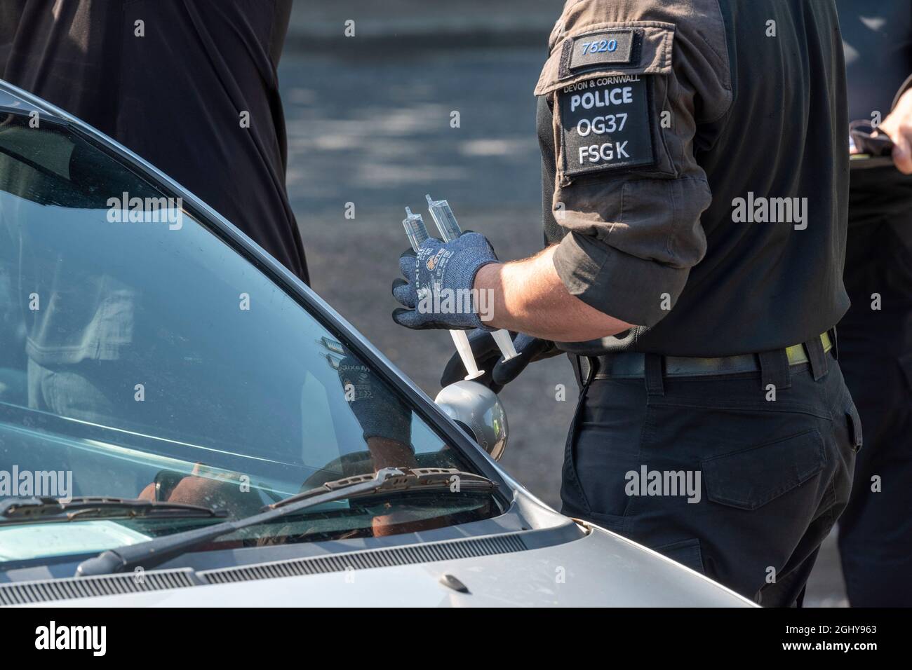 London, Großbritannien. September 2021. Ein Polizist aus Devon und Cornwall trägt einen Superklebstoff-Dissolver, um Demonstranten zu entfernen, die sich in ein Auto auf der A1020 einsperrten und um ein Auto herum klebten, das den Zugang zu dem für die DSEI (Defence and Security Equipment International) in Excel London aufgebauten Fahrzeug blockierte. Die vom 14. Bis 17. September stattfinden soll. Kredit: SOPA Images Limited/Alamy Live Nachrichten Stockfoto