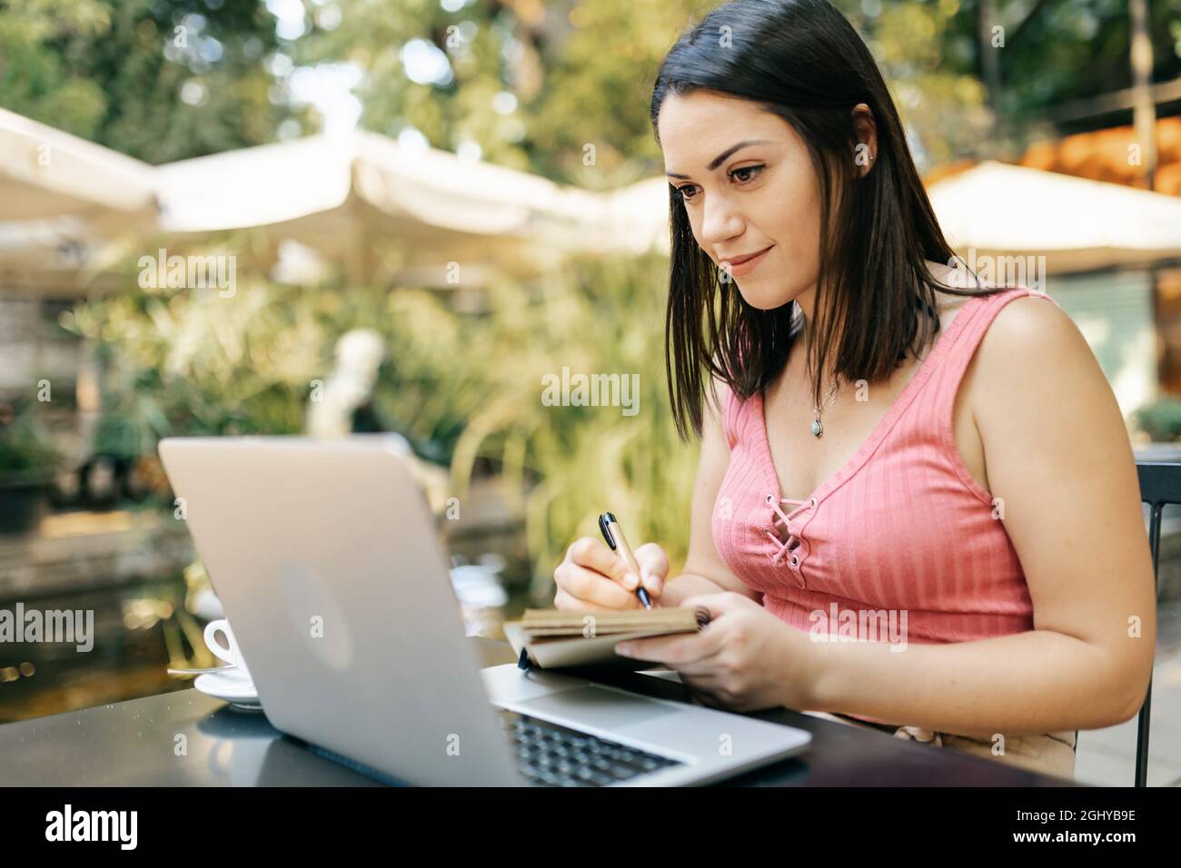 Tausendjährige junge hispanische Frau, die am Laptop arbeitet, während sie im Café sitzt Stockfoto