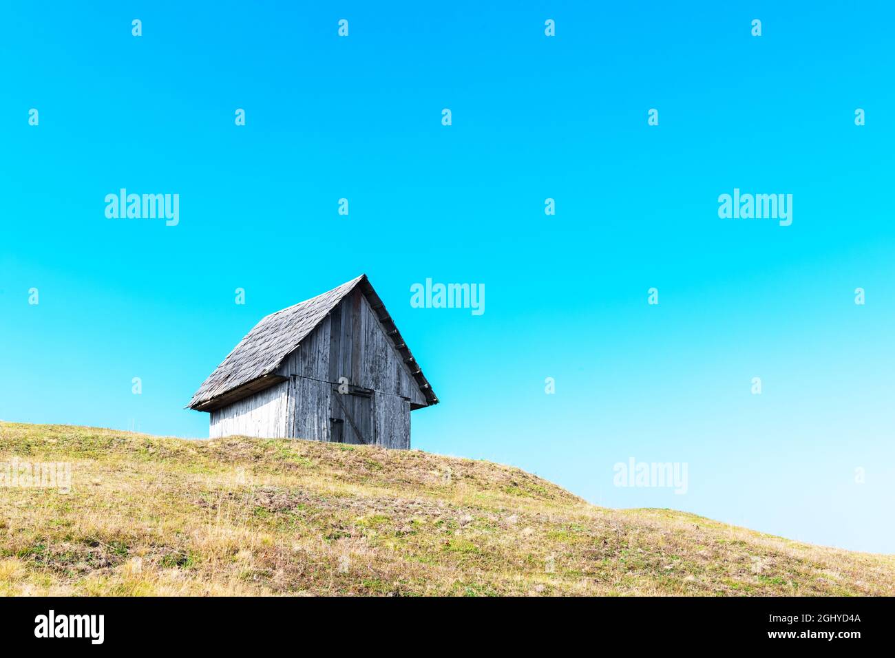 Malerische Herbstwiese mit altem Holzhaus und blauem Himmel in den Karpaten, Ukraine. Landschaftsfotografie Stockfoto