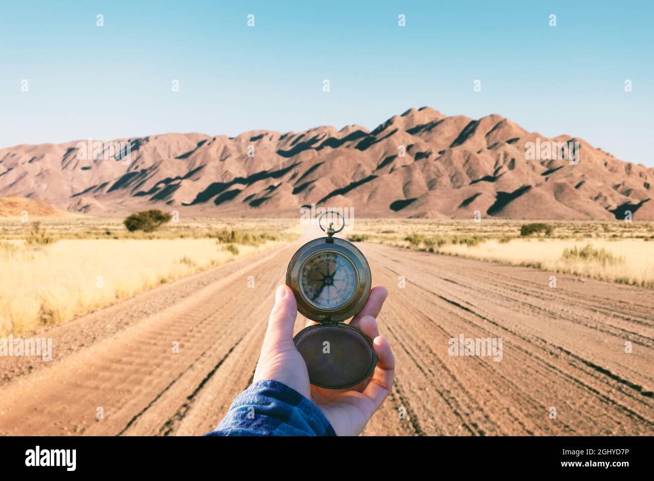 Mann mit altem Metallkompass in der Hand auf Schotterstraße in Namibia, Afrika. Reisekonzept. Landschaftsfotografie Stockfoto