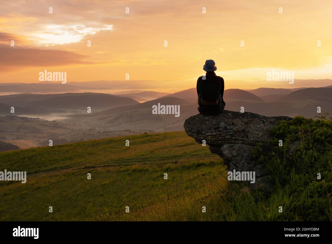 Allein Tourist am Rande des Berghügels gegen Die Kulisse eines unglaublichen Sonnenuntergangs Berglandschaft Stockfoto