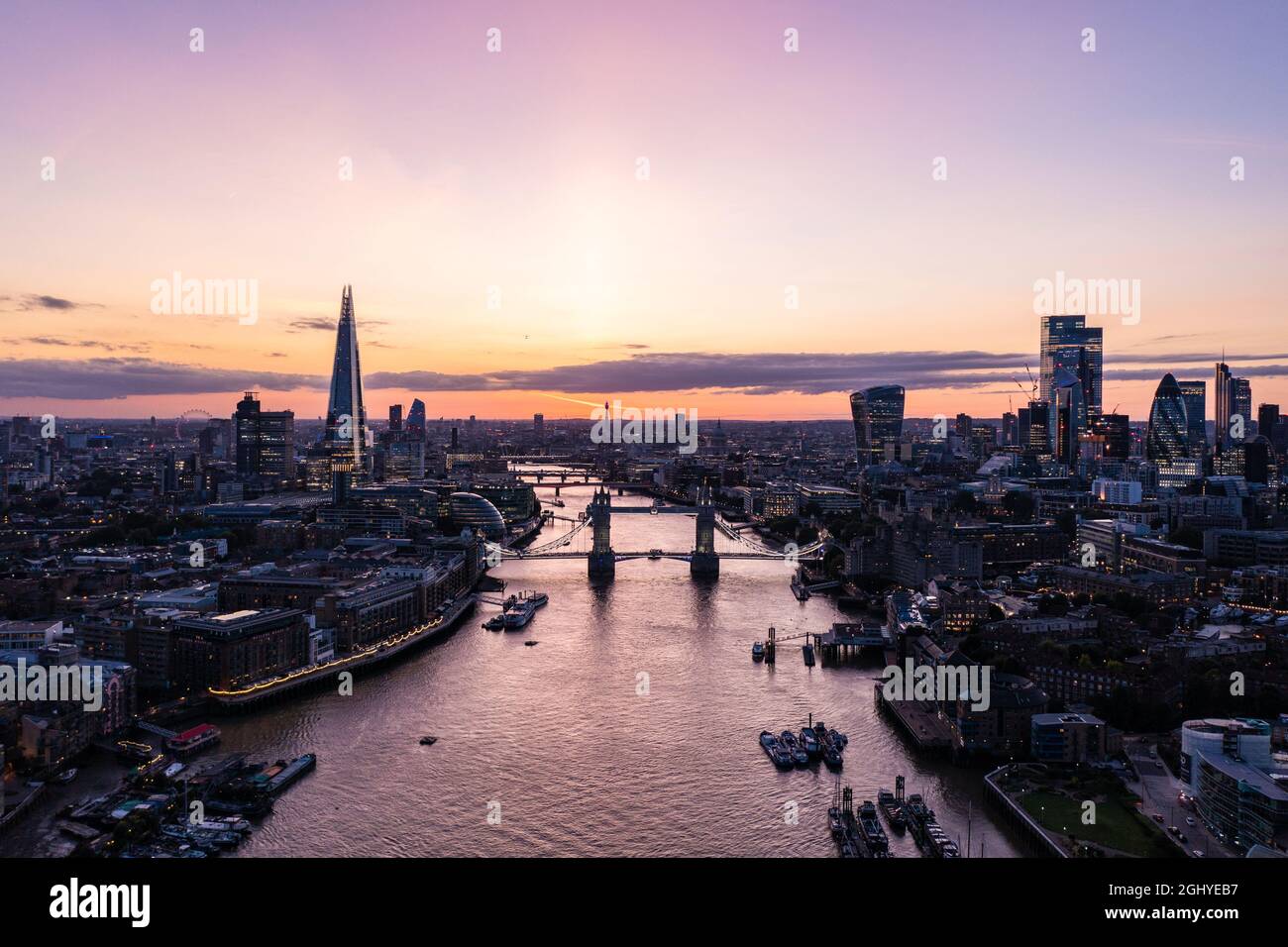 Drone Blick auf die berühmte Tower Bridge über dem Ozean umgeben von Gebäuden und Wolkenkratzern unter einer bewölkten Dämmerung und Dämmerung Morgen Stockfoto