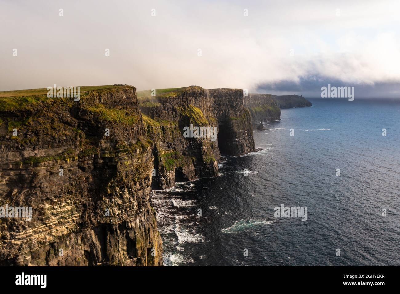 Wunderschöne und berühmte irische Klippen von Moher an der Westküste Irlands mit ruhigen und Meerwasser unter einem wolkenlosen weißen Himmel während des Tages Stockfoto