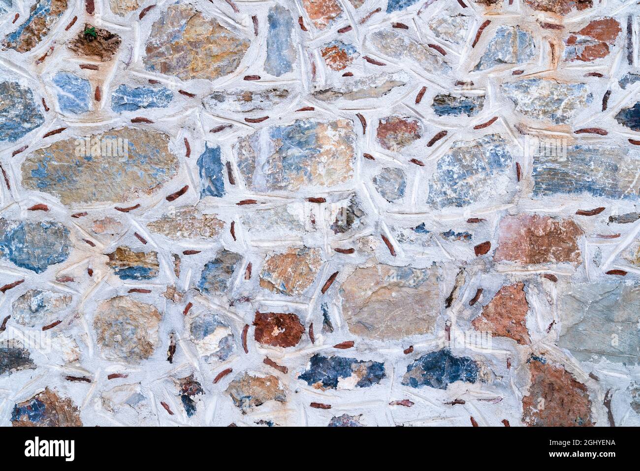 Hintergrundstruktur der Wand aus farbigen Steinen mit weißem Kitt. Stockfoto