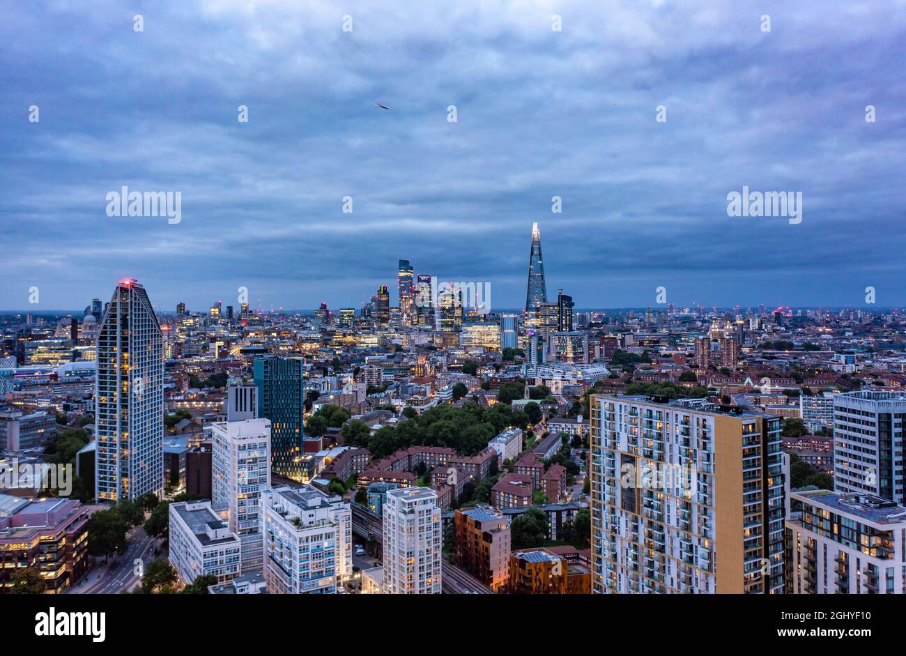 Hohe Gebäude umgeben von kleinen Gebäuden mit dem Dreiecks-Wolkenkratzer in der wunderschönen Stadt London an einem bewölkten Tag mit blauem Himmel Stockfoto
