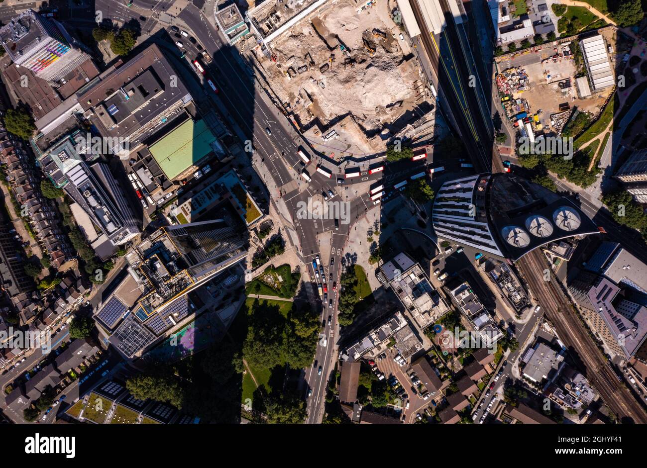 Blick aus der Vogelperspektive auf hohe Finanz- und Geschäftsgebäude mit Schatten und Autos, die sich an einem hellen, sonnigen Tag in der Londoner Stadt auf der Stadtstraße bewegen Stockfoto