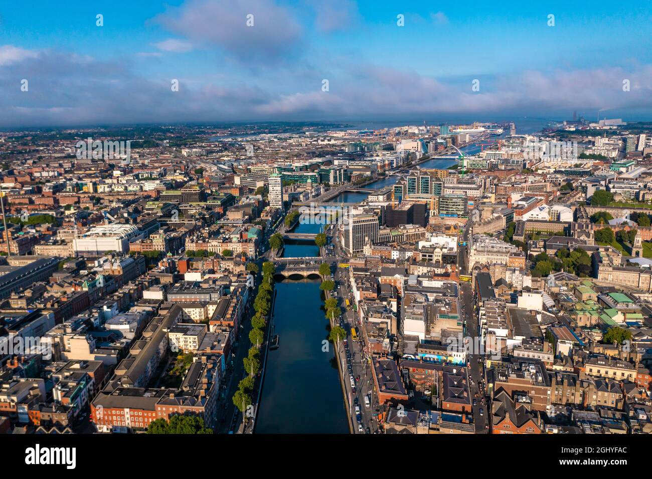 Eine Aufnahme der Skyline von Dublin mit einem Fluss, der an einem bewölkten Tag durch eine Brücke fließt, die zwei Seiten der Straße verbindet und von Gebäuden umgeben ist Stockfoto
