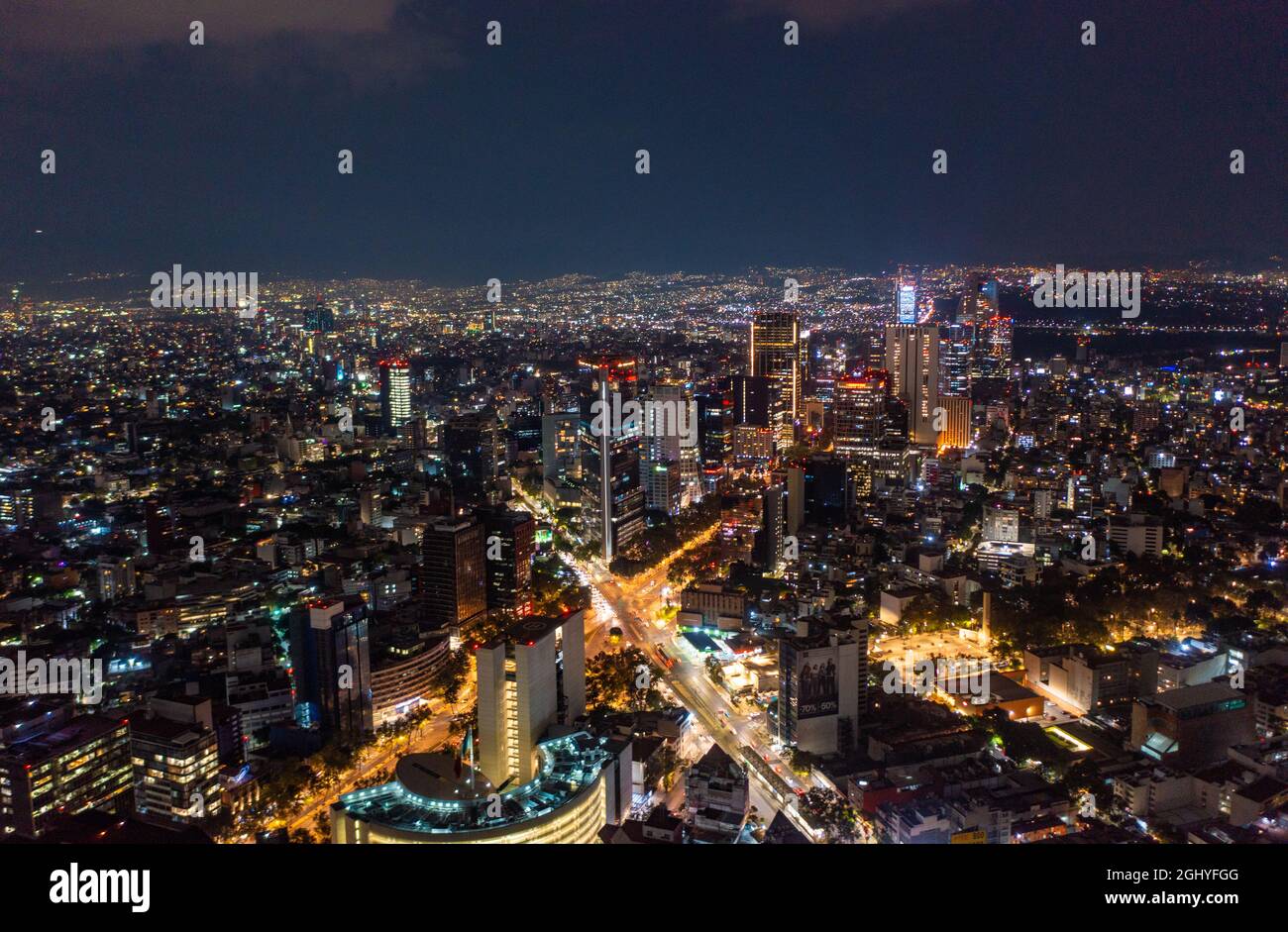 Luftaufnahme von schönen Gebäuden mit beleuchteten Beleuchtungen, die in Mexiko-Stadt gegen den dunklen schwarzen Himmel in der Nacht leuchten Stockfoto