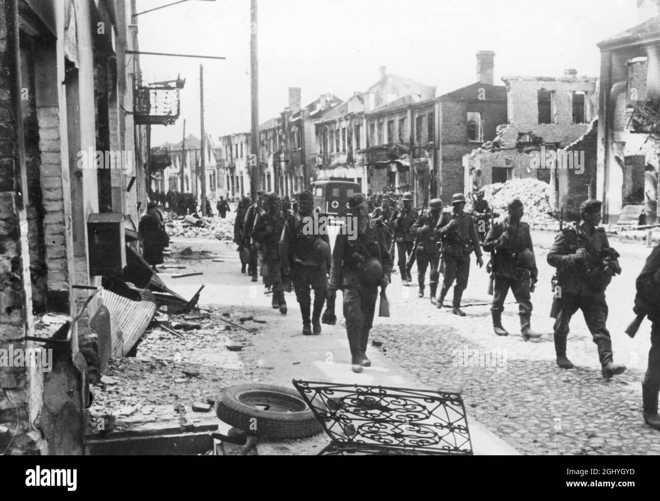 Eine Abteilung deutscher Infanterie marschiert durch eine zerstörte Stadt an der Ostfront. Stockfoto