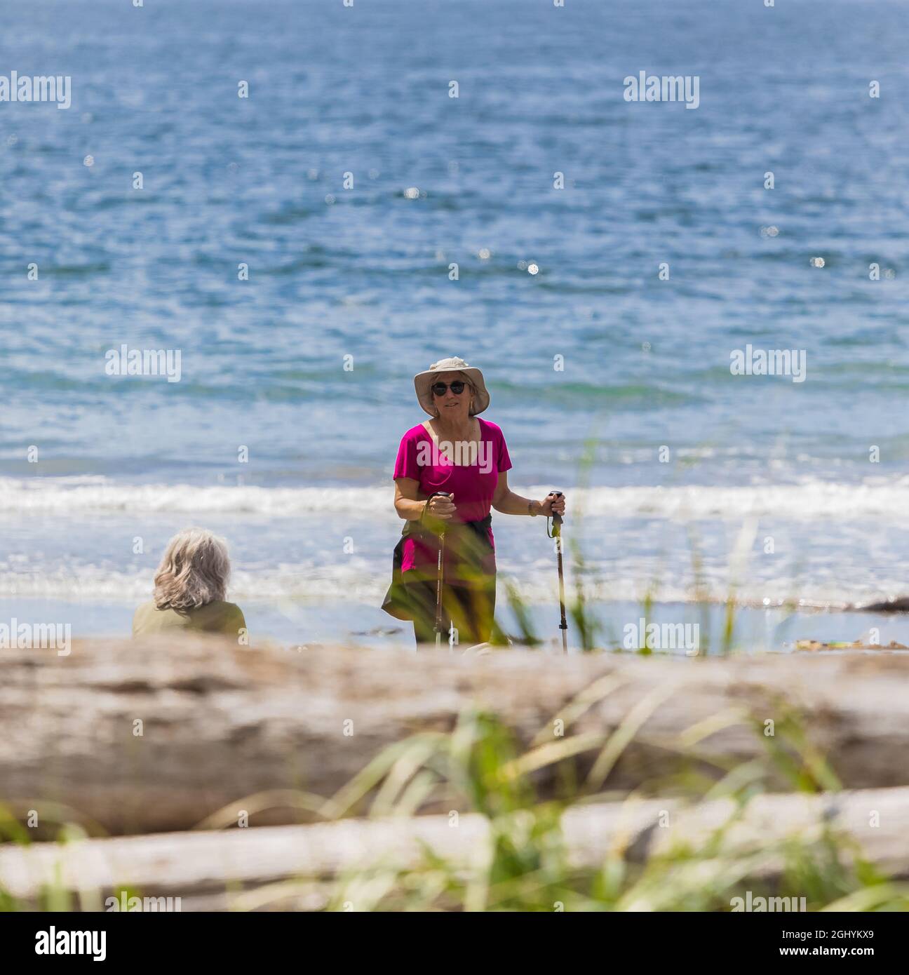Eine aktive Frau im Alter, die am 8,2021. August entlang der Küste am Sandstrand auf Vancouver Island, BC, Kanada, unterwegs ist. Selektiver Fokus, Reisefoto, Straßenansicht Stockfoto