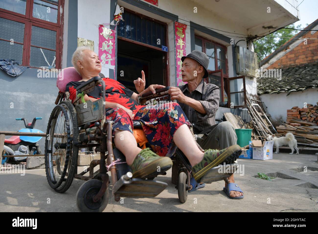 NANCHANG, 8. September 2021 (Xinhua) -- Luo Anmin spricht mit seiner Frau im Hof des Dorfes Xuluo im Bezirk Nanchang, Provinz Jiangxi, Ostchina, 5. September 2021. Luo Anmin ist 76 Jahre alt. 2008 litt seine Frau Wan Zhaolian an Hirntumor und verlor leider das Bewusstsein, aber Luo gab nie auf. Er sprach mit seiner Frau und gab ihr jeden Tag Massagen, in der Hoffnung, dass es ihr eines Tages besser gehen könnte. Nach drei Jahren liebevoller Fürsorge geschah das Wunder. 2011 erlangte Wan Zhaolian wieder das Bewusstsein, was Luo mehr Hoffnung gab, obwohl sie immer noch nicht sprechen und gehen konnte. Luo sagte, er liebe es Stockfoto