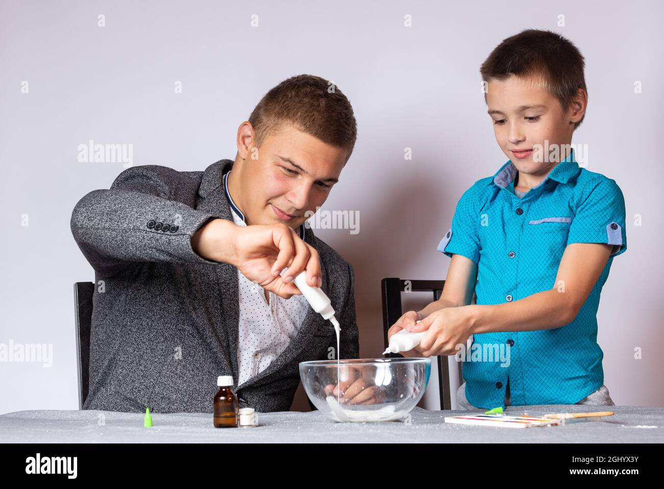 Konzept der chemischen aus- und Weiterbildung. Nahaufnahme eines Jungen und seines Vaters, die ein heimisches Experiment machten, Schleim aus Klebstoff, Natriumtetraborat A machten Stockfoto