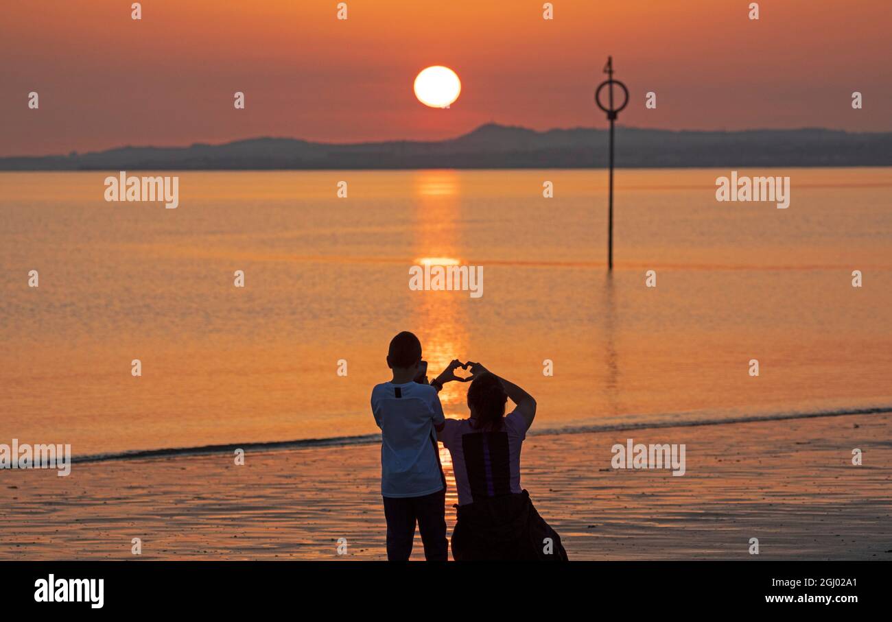 Portobello, Edinburgh, Schottland, UK Wetter. September 2021. Pauline und ihr Sohn Jacob fotografieren den Sonnenaufgang aus einem Herzen. Temperatur im Morgengrauen 13 Grad Celsius am Meer am Firth of Forth. Stockfoto