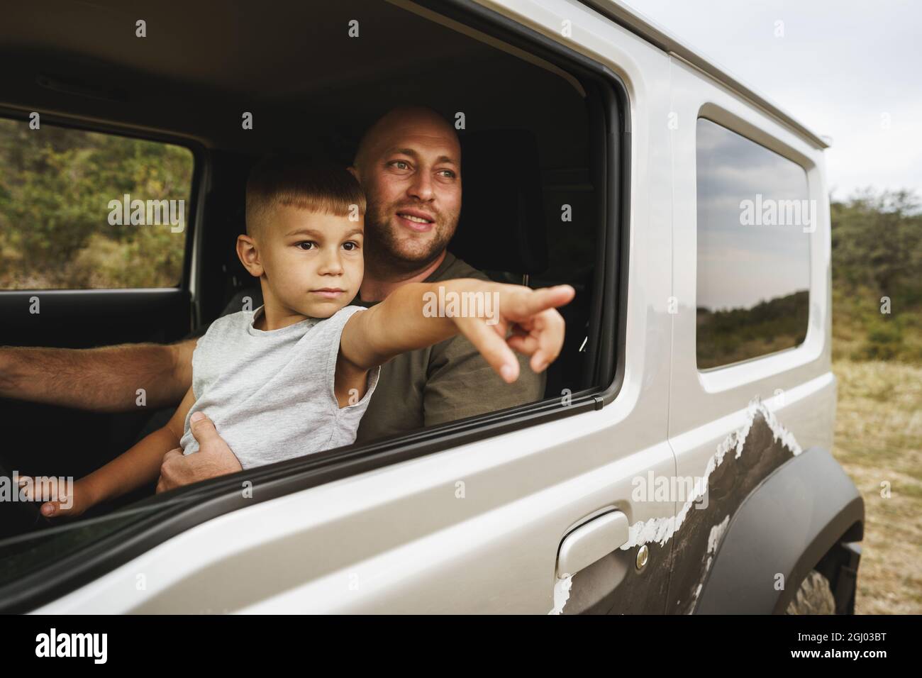 Vater lehrt den kleinen Sohn auf einer Autoreise zu fahren Stockfoto