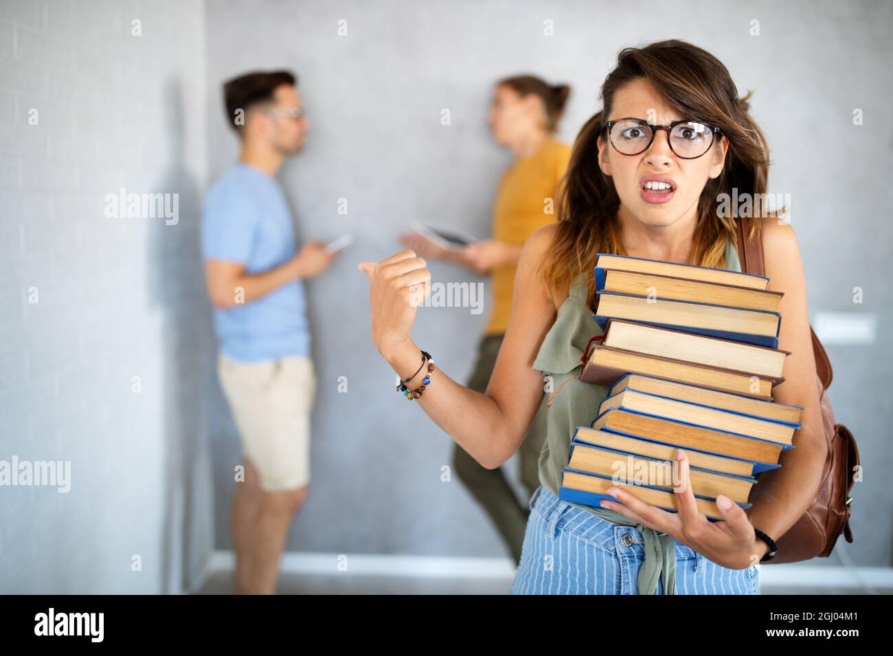 Unglücklich Student Mädchen Blick auf ihre faulen Kumpels, die sind Spielen mit dem Telefon statt zu arbeiten Stockfoto