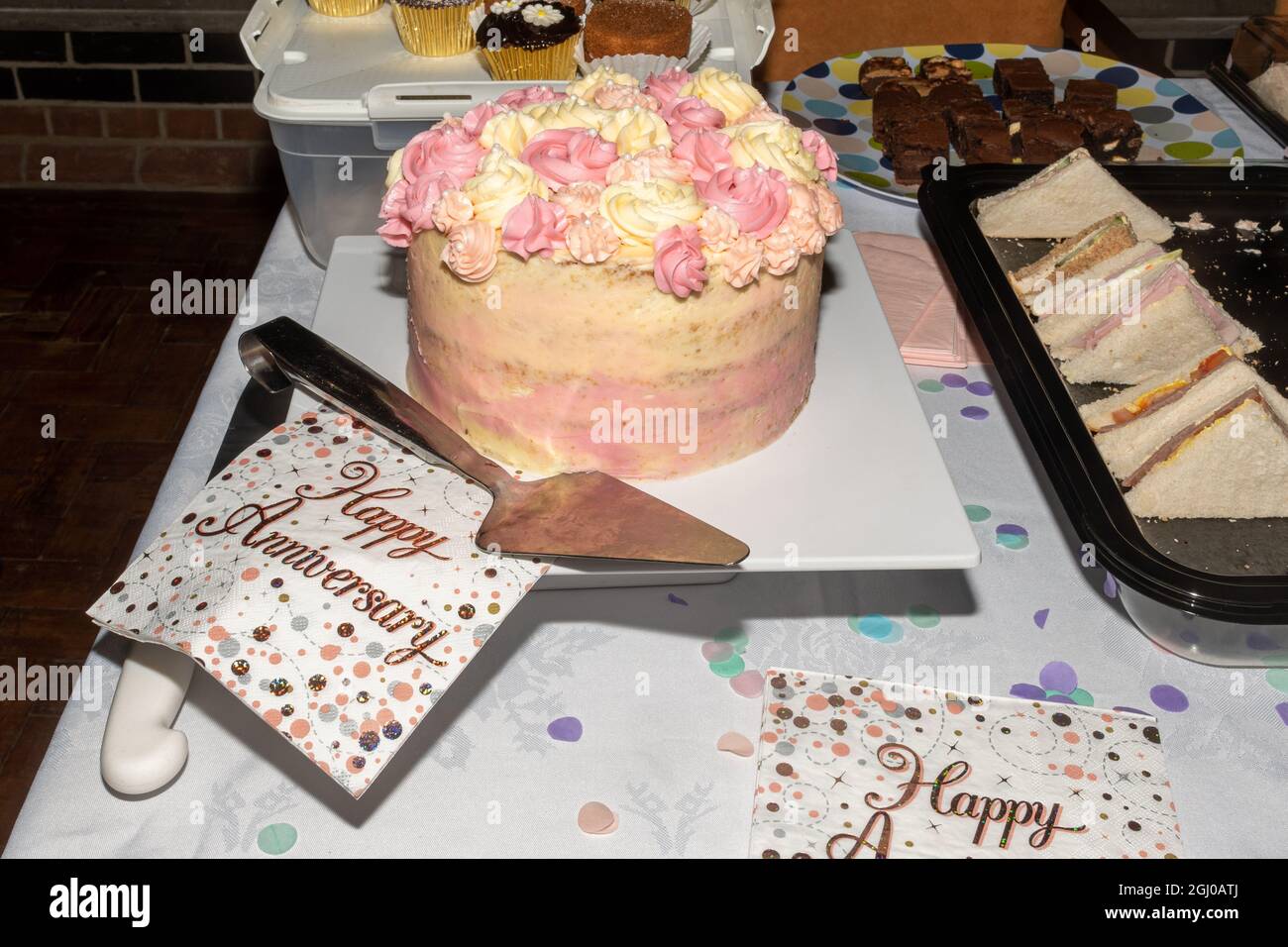 Dekorierter oder vereisten Kuchen für einen besonderen Anlass mit einem Buffet und Servietten zum Happy Anniversary Stockfoto