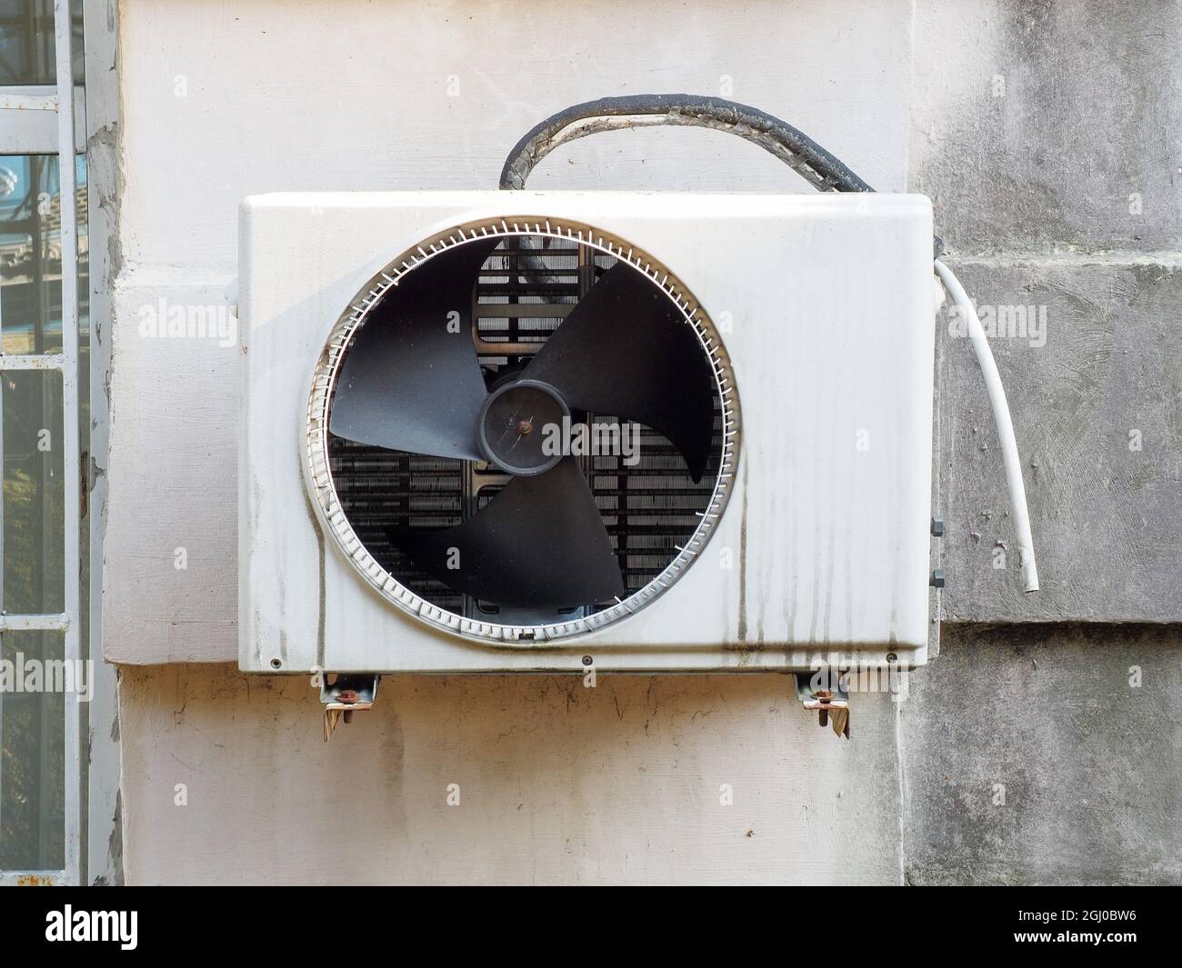 An der Wand hängt draußen eine Klimaanlage mit Ventilator und einem  Abflussrohr Stockfotografie - Alamy