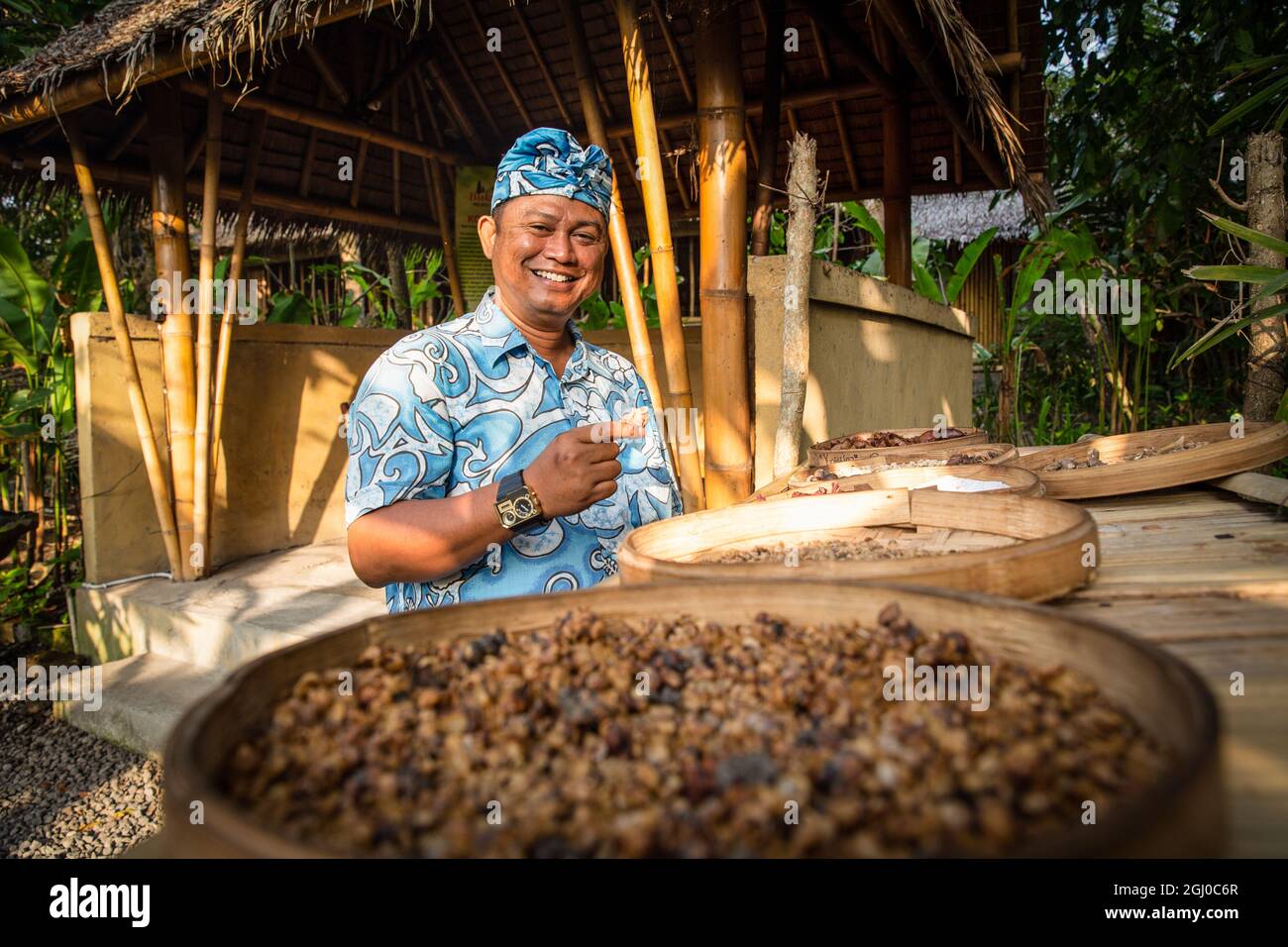 Bali - Indonesia 10.21.2015 - Balinesischer Indonesier in traditionellen Tüchern, lächelnd und mit luwak-Kaffeesamen Stockfoto