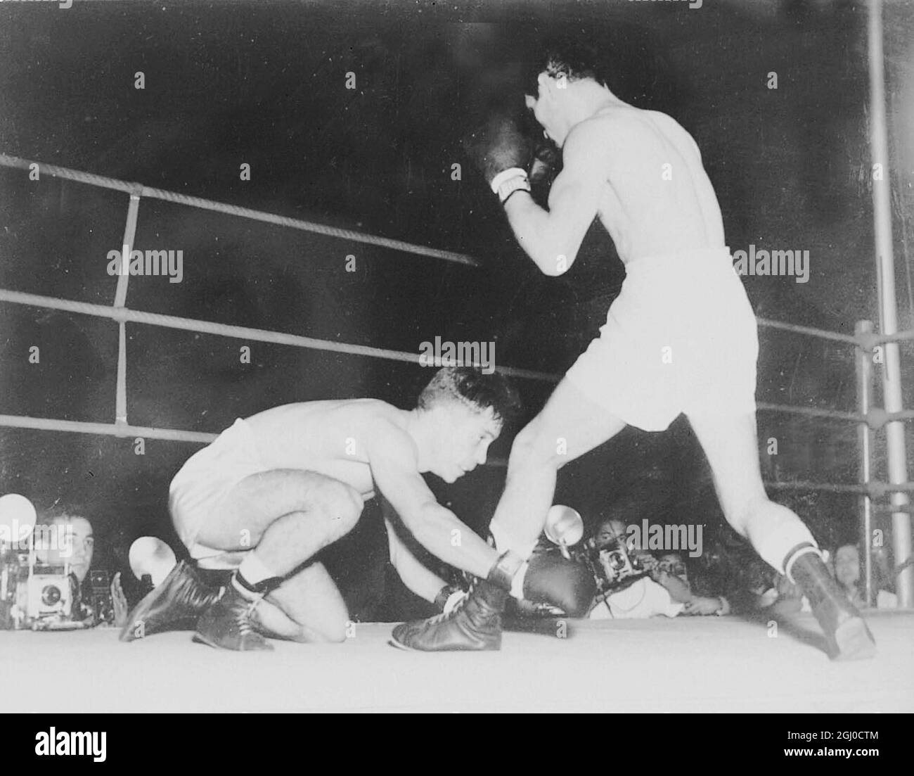 Pascuel Perez ( rechts ), der Weltmeister im Fliegengewicht, bringt den spanischen Young Martin in der dritten Runde ihres 15-Runden-Weltmeisterschaftskampfes in Buenos Aires, Argentinien, am 12. Dezember 1957 ins Rennen Stockfoto