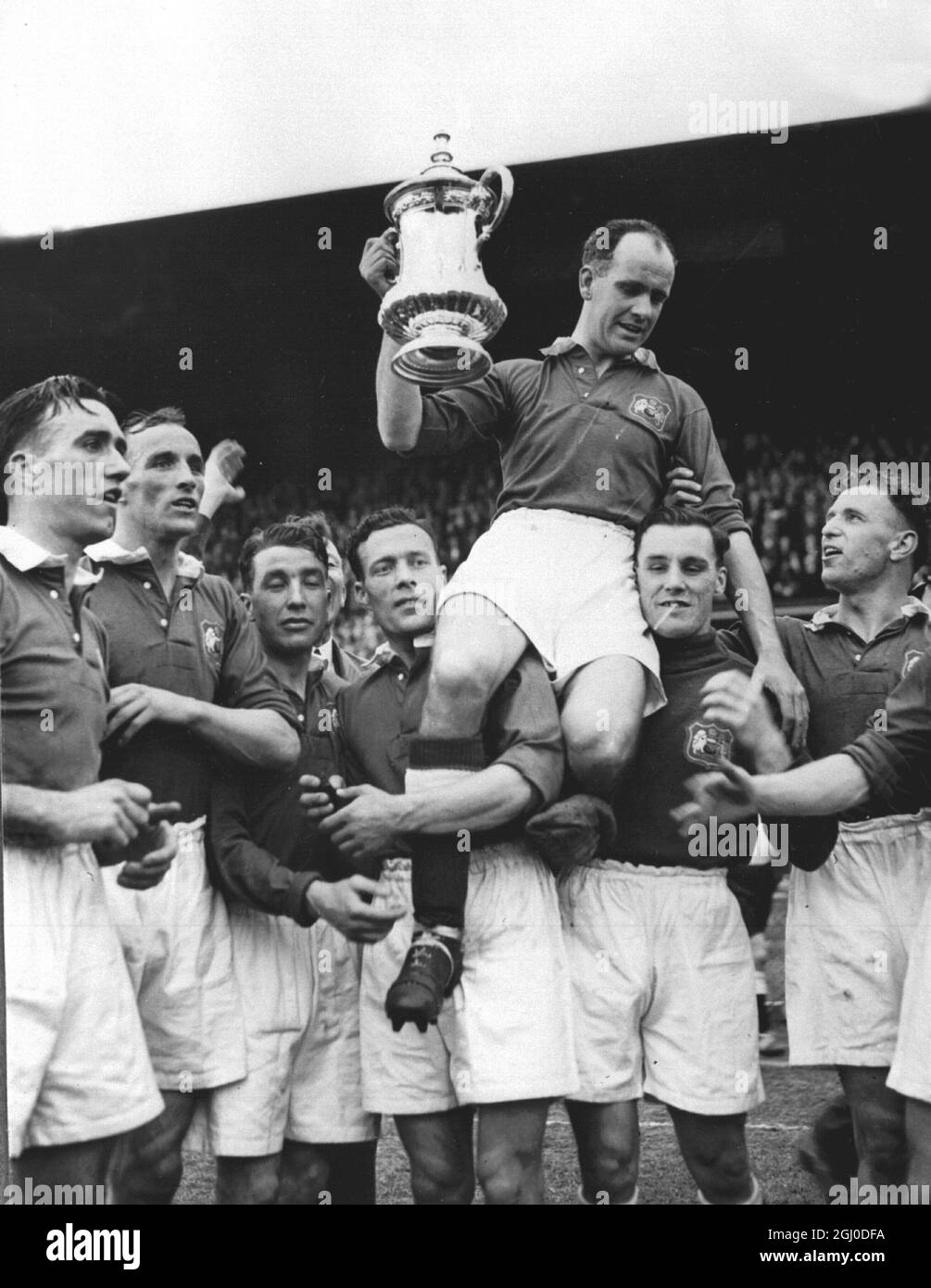 1948 FA Cup Final Manchester United gegen Blackpool John Carey wird von seinen Teamkollegen mit dem FA Cup gehalten, nachdem Manchester United Blackpool im Finale 4-2 in Wembley besiegt hatte. April 1948 Stockfoto