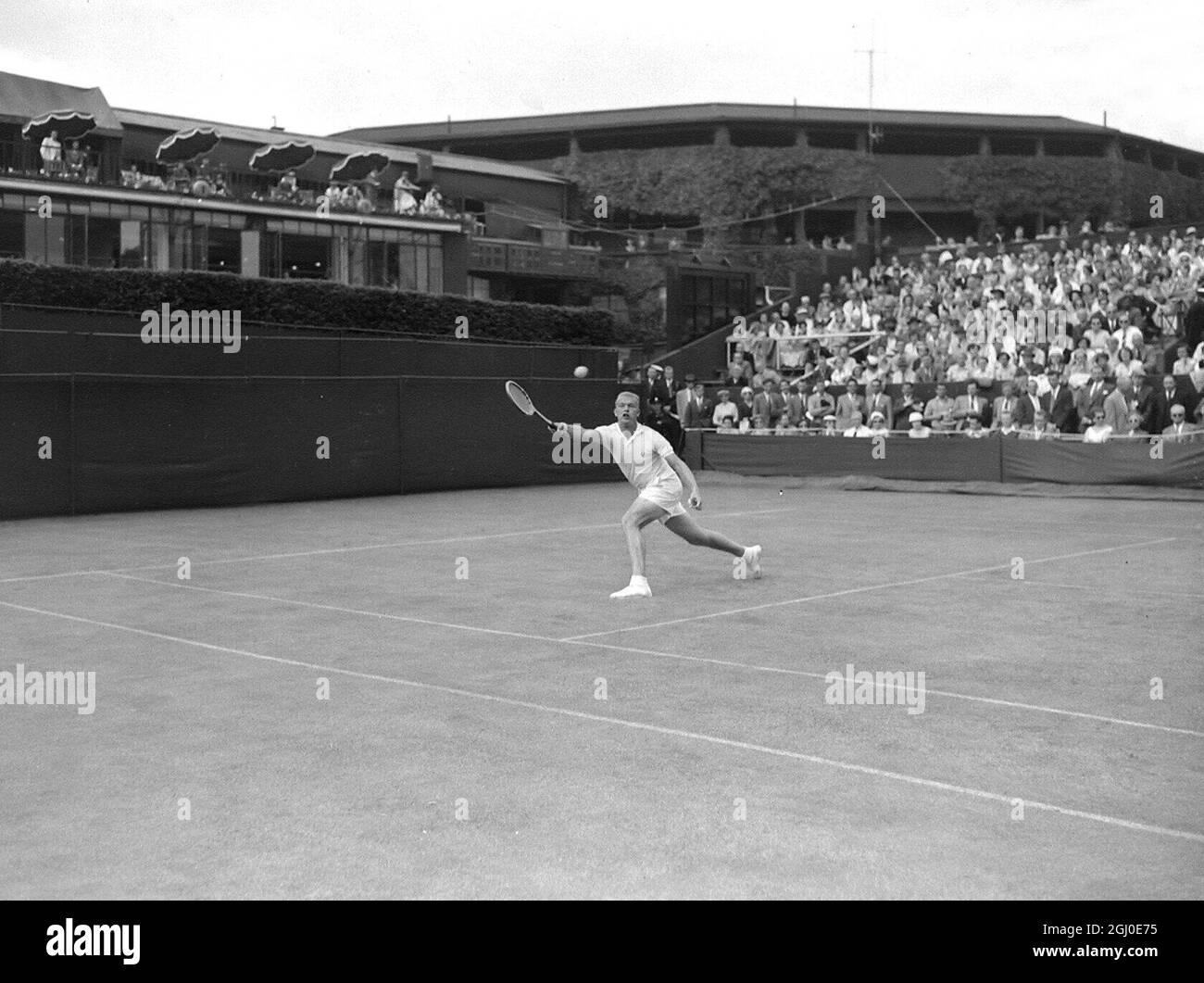 Eine lange Strecke, aber Ronald Holmberg (USA) schafft es einfach, einen Ball an Art Larson (USA) während ihres Einzelkampfs bei den Wimbledon Lawn Tennis Championships am ersten Tag zurückzugeben. Larson gewann das Spiel 5-7, 6-3, 6-4, 6-3. Juni 1956 Stockfoto