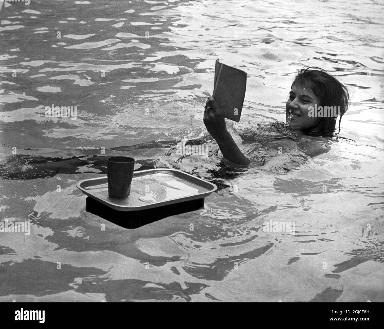Die 18-jährige Michelle Kalli, die Pigalle-Tänzerin, genießt eine gute Geistergeschichte, die im Oasis-Swimmingpool im Londoner Holborn schwimmt. Juli 1962 Stockfoto