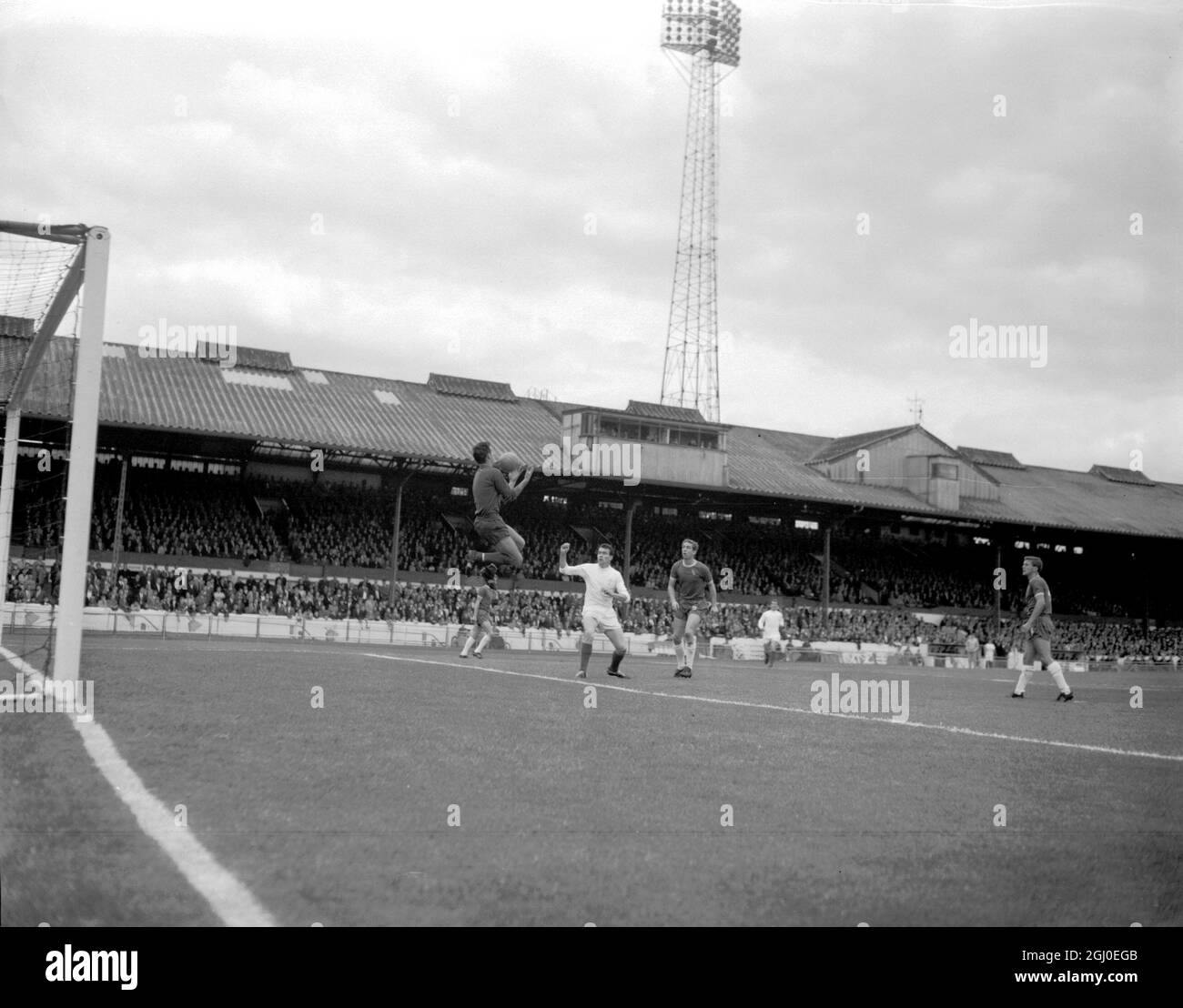 Chelsea-Torwart Peter Bonetti springt um den Ball zu holen, während Jim Storrie, der Leeds United Center nach vorne blickt. September 1964. Stockfoto