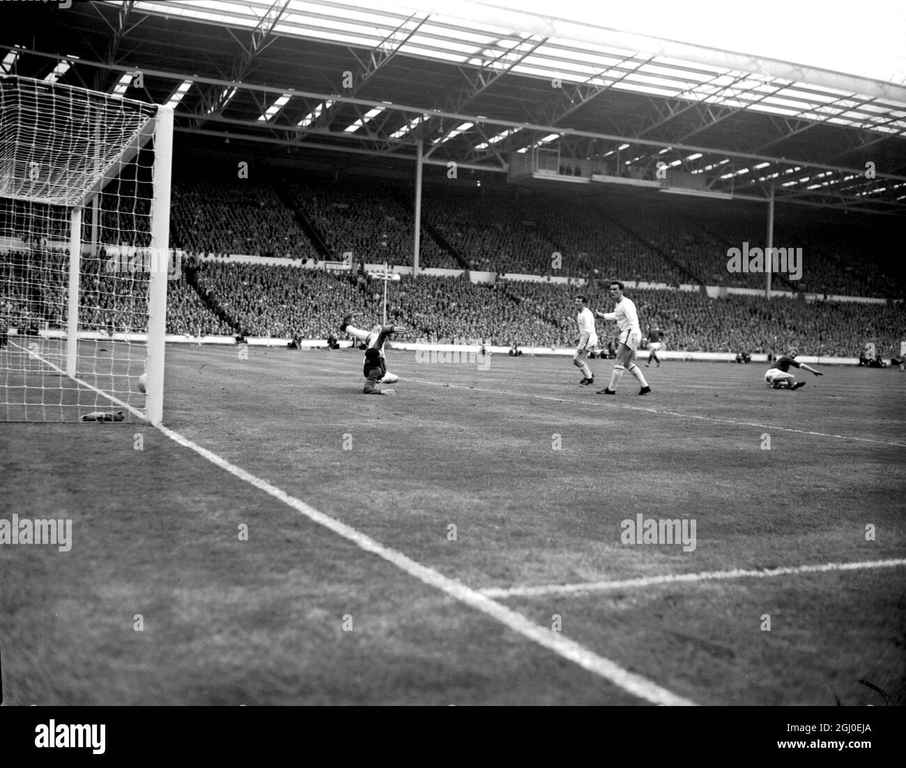 1963 FA Cup Finale Manchester United V Leicester City. Dennis Law, die linke Innenverteidigerin von Manchester United (ganz rechts, am Boden) erzielt das erste Tor für sein Team, während zwei nicht identifizierte Verteidiger von Leicester City Torhüter Gordon Banks vergeblich beim Tauchen zusehen. Manchester United besiegte Leicester City 3-1 und gewann den FA Cup. Mai 1963. Stockfoto