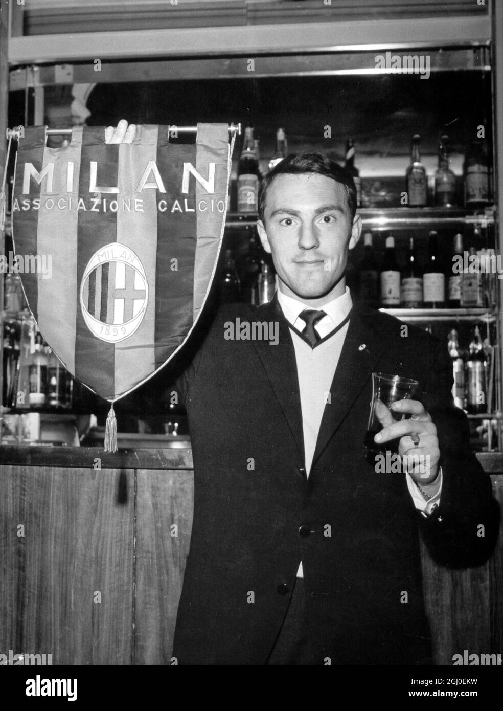 Jimmy Greaves, England und Chelsea Inside, der vom Milan Soccer Club unterzeichnet wurde, hält eine Flagge des Milan Soccer Teams, als er auf einen Toast seiner neuen Teamkollegen bei seiner Ankunft in Mailand reagiert. Mai 1961 Stockfoto