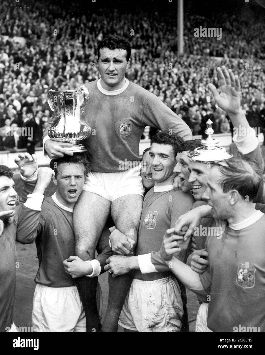 Manchester United captrain Noel Cantwell wird von seinen Teamkollegen geleitet, wobei der FA Cup nach der Präsentation von H.M. der Königin ausgetragen wird. United hatte Leicester City 3-1 besiegt, um den FA Cup zu gewinnen. April 1963. Stockfoto