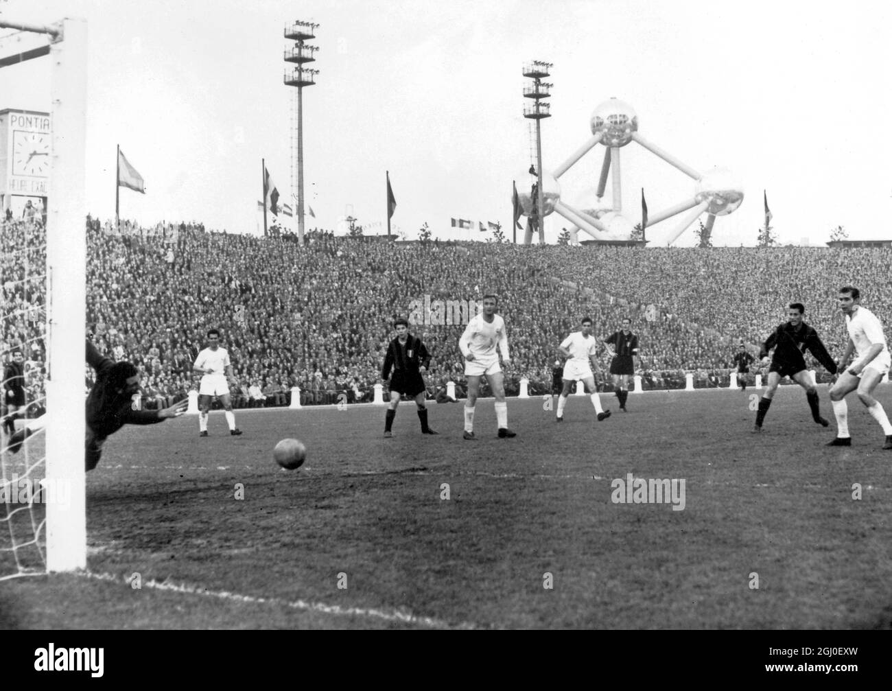 Real Madrid wurde erneut Europameister, als sie Mailand im Heysel-Stadion, Brüssel, 3-2, besiegten. Real Madrid Torwart Alonso taucht auf einen Schuss von Mailand Zentrum vorne Schiaffino, der in der zweiten Hälfte getroffen, und ist als zweiter von rechts abgebildet. Das Atomium, das Zentrum der Brüsseler Messe, ist im Hintergrund zu sehen. Mai 1958. Stockfoto