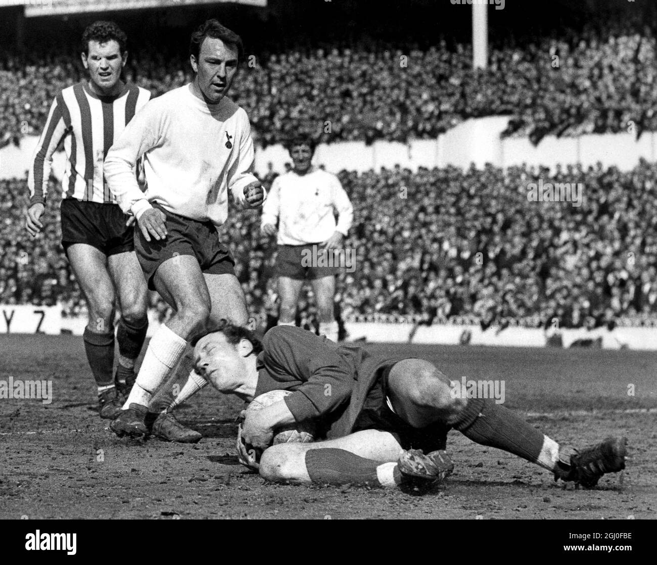Tottenham Hotspur gegen Southampton-Torhüter Eric Martin rettet während des Spiels in der White Hart Lane vor Jimmy Greaves. Im Hintergrund ist Southampton Mitte Hälfte John McGrath. April 1968. Stockfoto