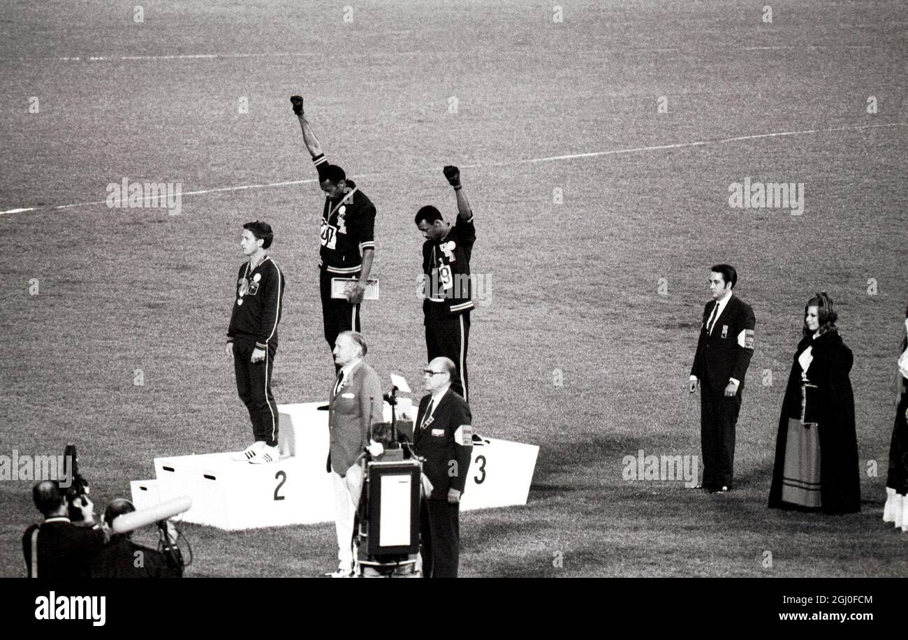Die Olympischen Spiele 1968, die Gold- und Bronzemedaillengewinnerinnen von Mexiko-Stadt, Tommie Smith (Mitte) und John Carlos (rechts), heben ihre Arme als „schwarze Macht“-Geste während der Zeremonie der Olympischen Spiele. Smith hatte beim 200-Meter-Rennen einen Weltrekord von 19.8 Sekunden aufgestellt. Jeder Mann trug einen schwarzen Handschuh an einer Hand und hob ihn, wobei die Faust geballt wurde, als die US-Flagge angehoben wurde. Peter Norman aus Australien (links) gewann die Silbermedaille. 16. Oktober 1968. Stockfoto