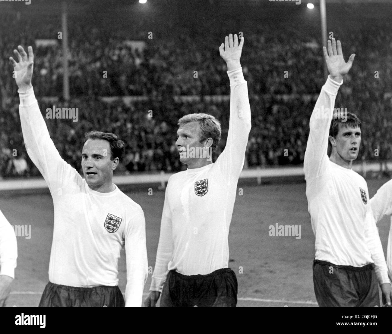 1966 World Cup England gegen Portugal England Kapitän Bobby Moore (Mitte) und die Teamkollegen George Cohen (links) und Geoff Hurst winken nach dem Halbfinale der Weltmeisterschaft über Portugal in die Menge. Juli 1966. Stockfoto