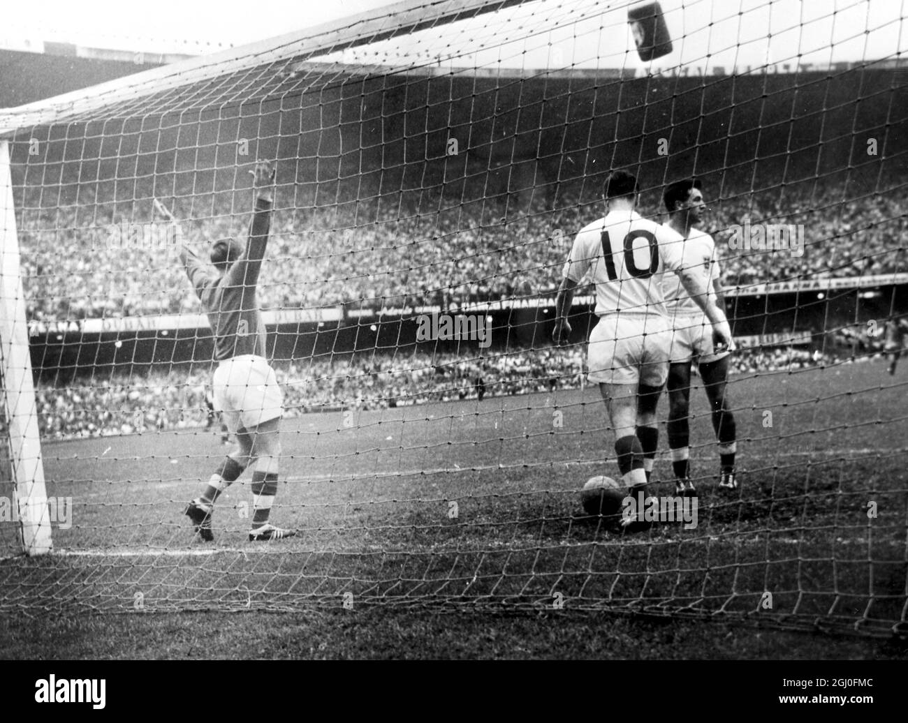 Brasilien gegen England Englands Torhüter Hopkinson, links wirft seine Arme nach Brasilien, nachdem Brasilien beim internationalen Spiel in Rio ihr erstes Tor erzielt hat. Englands Johnny Haynes (Nr. 10) wird gesehen, wie er den Ball aus dem Netz zurückholen kann. Brasilien gewann das Spiel mit zwei Toren auf Null. Mai 1957 Stockfoto