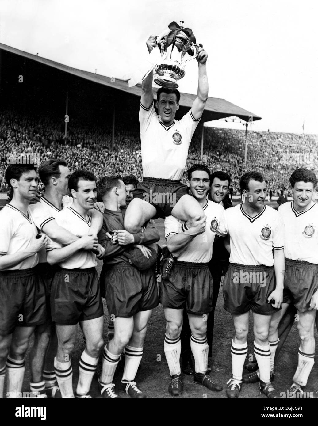 1958 FA Cup Final Manchester United gegen Bolton Wanderers Nat Lofthouse, der Bolton-Mitstreiter und Kapitän, der beide Tore seiner Mannschaft erzielte, wird außerhalb des Feldes geleitet, während er die FA Cup-Trophäe hält. Mai 1958 Stockfoto