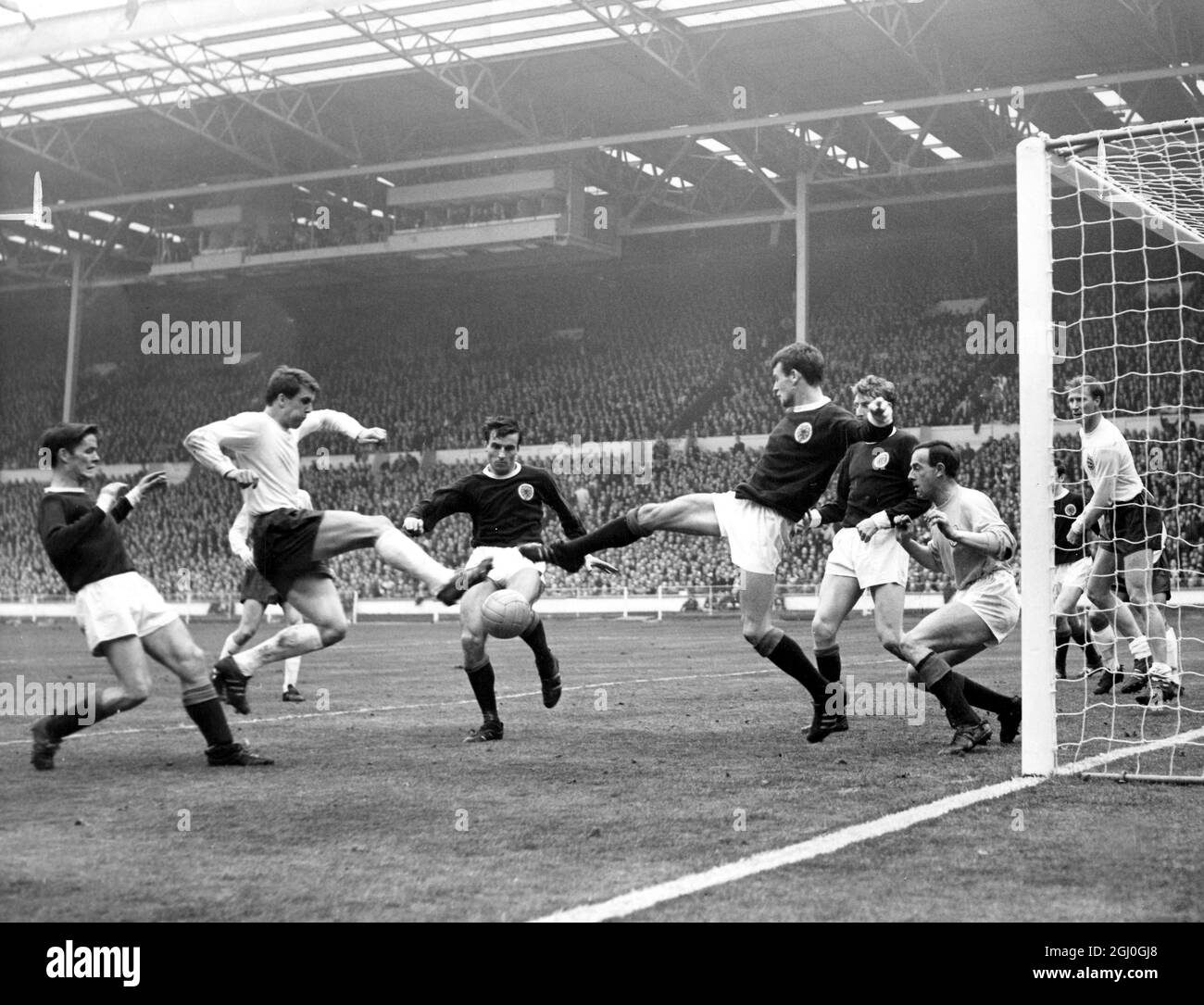 England gegen Schottland in einem EM-Qualifikationsspiel - Schottland drängen in den letzten Minuten ihren Torhügel, während Geoff Hurst (England) und Eddie McCreadie (Schottland) versuchen, den Ball zu erreichen. April 1967 Stockfoto