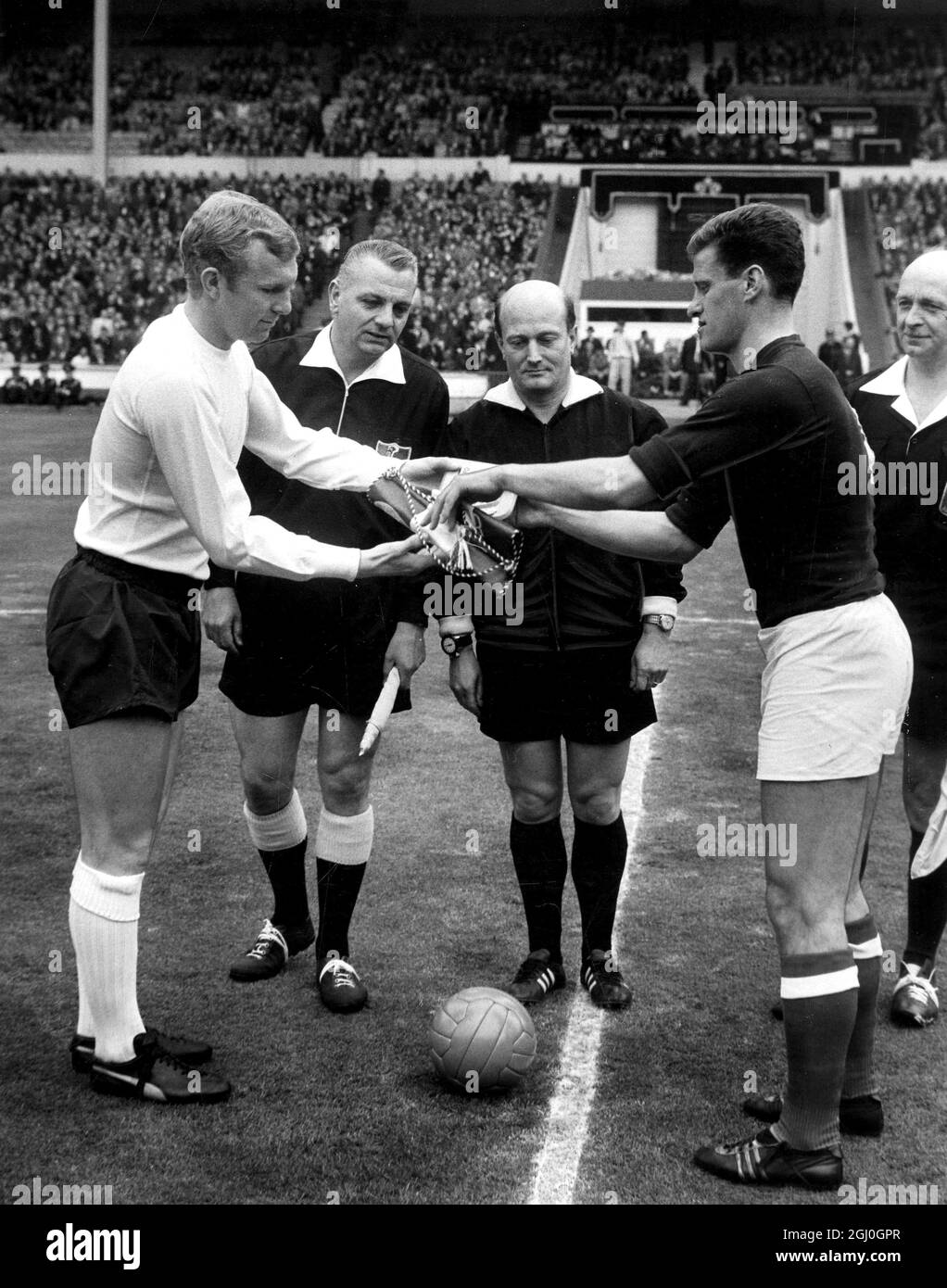 England gegen Ungarn Bobby Moore tauscht sich vor dem Spiel mit Ferenc Sipos, dem ungarischen Kapitän, aus, der vom Schiedsrichter P Schwinte aus Frankreich beobachtet wurde. Mai 1965 Stockfoto