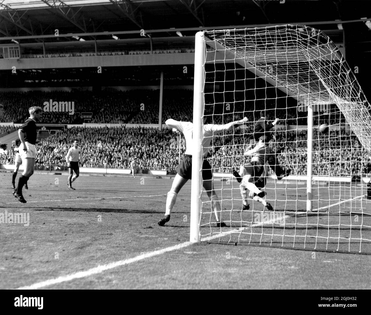 10. April 1965: Schottland gegen England in Wembley. Foto zeigt: Ian St John (dunkler Streifen, mitten in der Luft), bewertet Schottlands Ausgleichstor, um es 2:2 zu erreichen. Unter dem Ansturm geht Englands Torhüter Gordon Banks nieder. Stockfoto