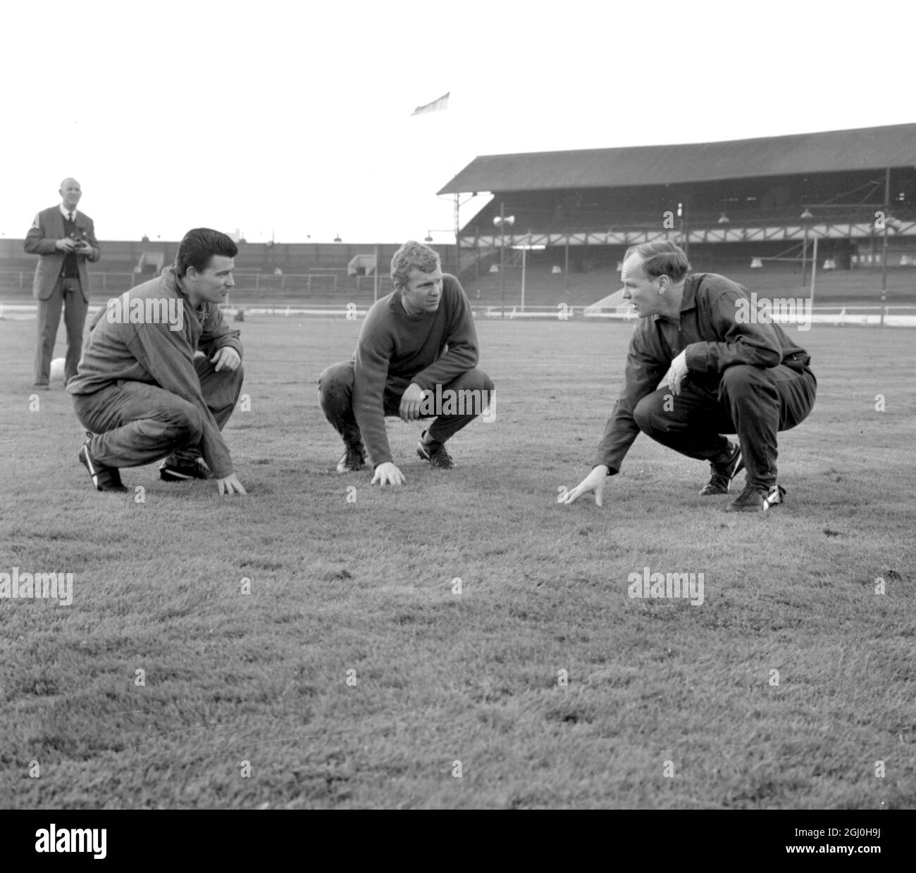 Das West Ham Utd-Team kommt im West Ham Greyhound Stadium zu einer Trainingseinheit auf dem üppigen Rasen, die dem des Wembley Stadions ähneln wird, wo sie Preston North End im Finale am 2. Mai treffen werden. Die hier gezeigten sind von links nach rechts:Roger Byrne, der mittlere nach vorne, Bobby Moore, Kapitän und halber Rücken, und Manager Ron Greenwood. April 1964. Stockfoto