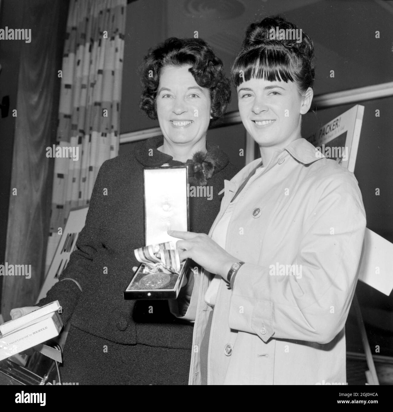 London: Janet Simpson, eine der britischen Bronzemedaillengewinnerinnen bei den Olympischen Spielen in Tokio, ist heute hier mit ihrer Mutter, Frau Violet Simpson, die bei den Olympischen Spielen in Los Angeles 1932 eine Bronzemedaille gewonnen hat, abgebildet. Janet flog heute Morgen von Tokio mit dem ersten Kontingent des britischen Olympischen Teams nach Hause zurück. Die Party war später Gäste der Queen beim ersten von zwei Buffetmahlzeiten im Buckingham Palace für Mitglieder und Beamte des olympischen Teams. 27. Oktober 1964 Stockfoto