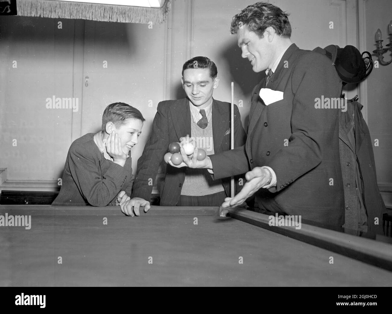 Freddy Mills zeigt, wie viele Snookerbälle er in der Hand halten kann - als er heute Burroughes und Watts Hall, Soho, Square, London besuchte, um sich die Boys Billiards Championship anzusehen. Erstaunt sehen wir den Halbfinalisten Colin Smith im Alter von 14 Jahren von Crook, County Durham, und den Finalisten Jack Carney von Pondardawe, nahe Swansea, von links nach rechts. 2. Januar 1948. Stockfoto