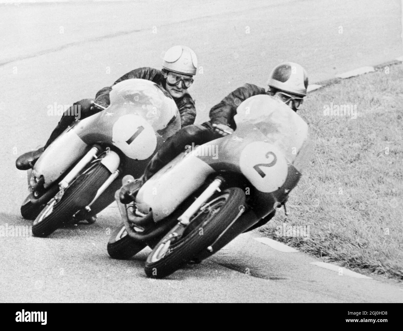 Assen, Holland: Großbritannien Mike Hailwood (N0 . 1), der Weltmeister im Motorradsport, fährt auf einem Vierzylinder-Italiener M.V., folgt Teamkollegen Giacomo Agostini (N0.2) bei der Runde einer Kurve während des Senior Dutch T.T. Hailwood, der kürzlich den Isle of man Senior T.T. gewann, konnte am 26. Juni in Assen einen neuen Rekord auflegen, als er nach einem großen Duell mit Agostini das Rennen gewann. Seine Zeit für das 96.6-Meilen-Rennen war das Duell mit Agostini. Seine Zeit für das 96.6-Meilen-Rennen betrug 64:59.6 Sekunden - ein Durchschnitt von 88.4 M.P.H. 29. Juni 1965 Stockfoto