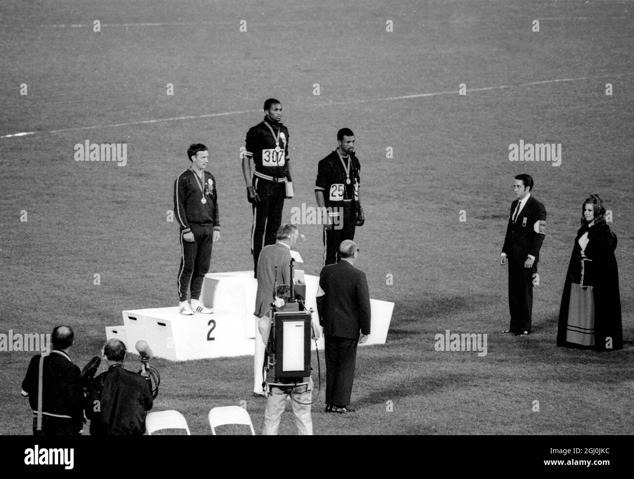 Die Olympischen Spiele 1968, die Gold- und Bronzemedaillengewinnerinnen von Mexiko-Stadt, Tommie Smith (Mitte) und John Carlos (rechts), heben ihre Arme als „schwarze Macht“-Geste während der Zeremonie der Olympischen Spiele. Smith hatte beim 200-Meter-Rennen einen Weltrekord von 19.8 Sekunden aufgestellt. Jeder Mann trug einen schwarzen Handschuh an einer Hand und hob ihn, wobei die Faust geballt wurde, als die US-Flagge angehoben wurde. Perter Norman aus Australien (links) gewann die Silbermedaille. Oktober 1968. Stockfoto