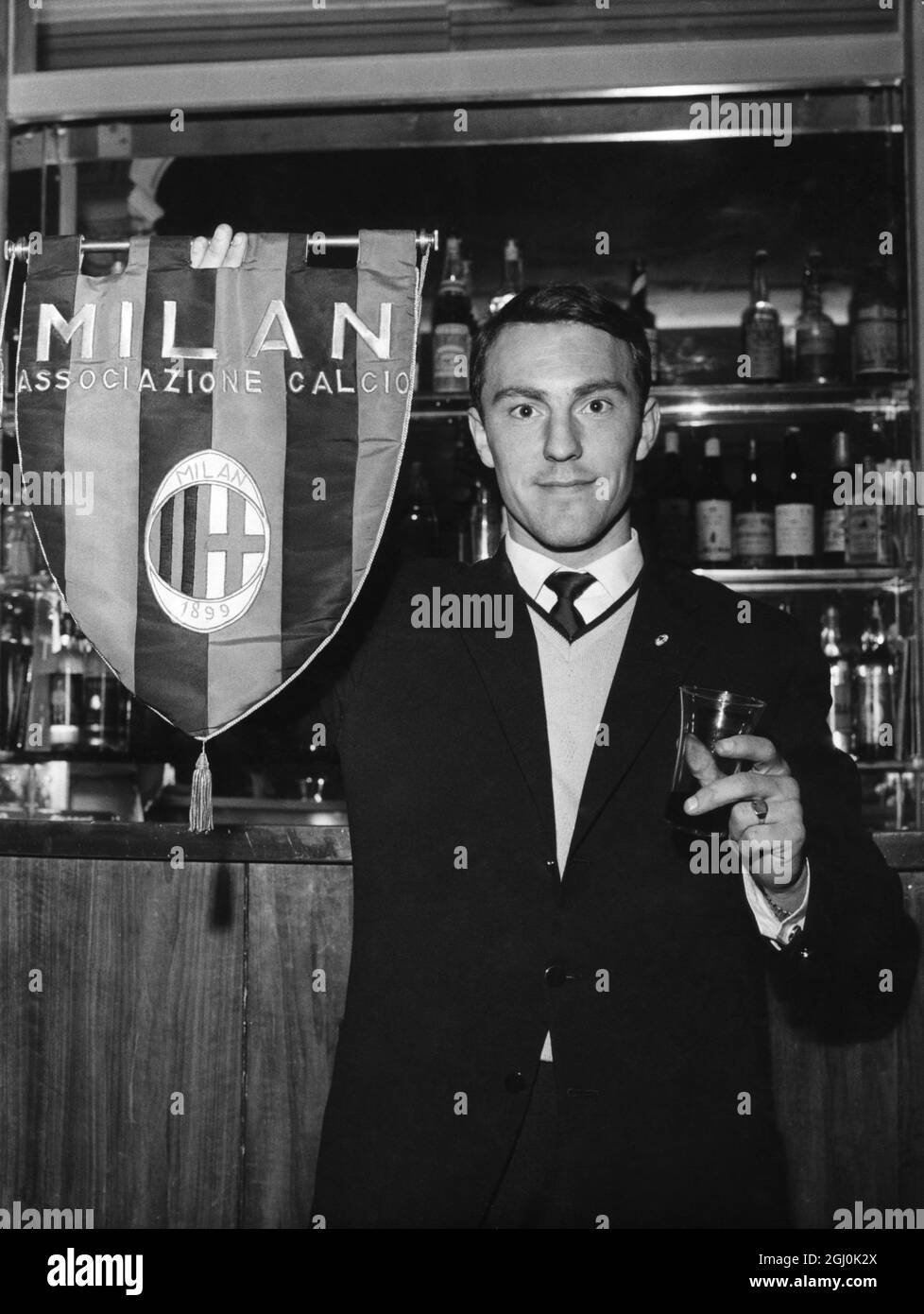 Jimmy Greaves, England und Chelsea, die vom Milan Soccer Club unterzeichnet wurden, hält eine Mannschaftsflagge von Milan Soccer, als er auf einen Toast seiner neuen Mannschaftskollegen bei seiner Ankunft in Mailand reagiert. Mai 1961 Stockfoto