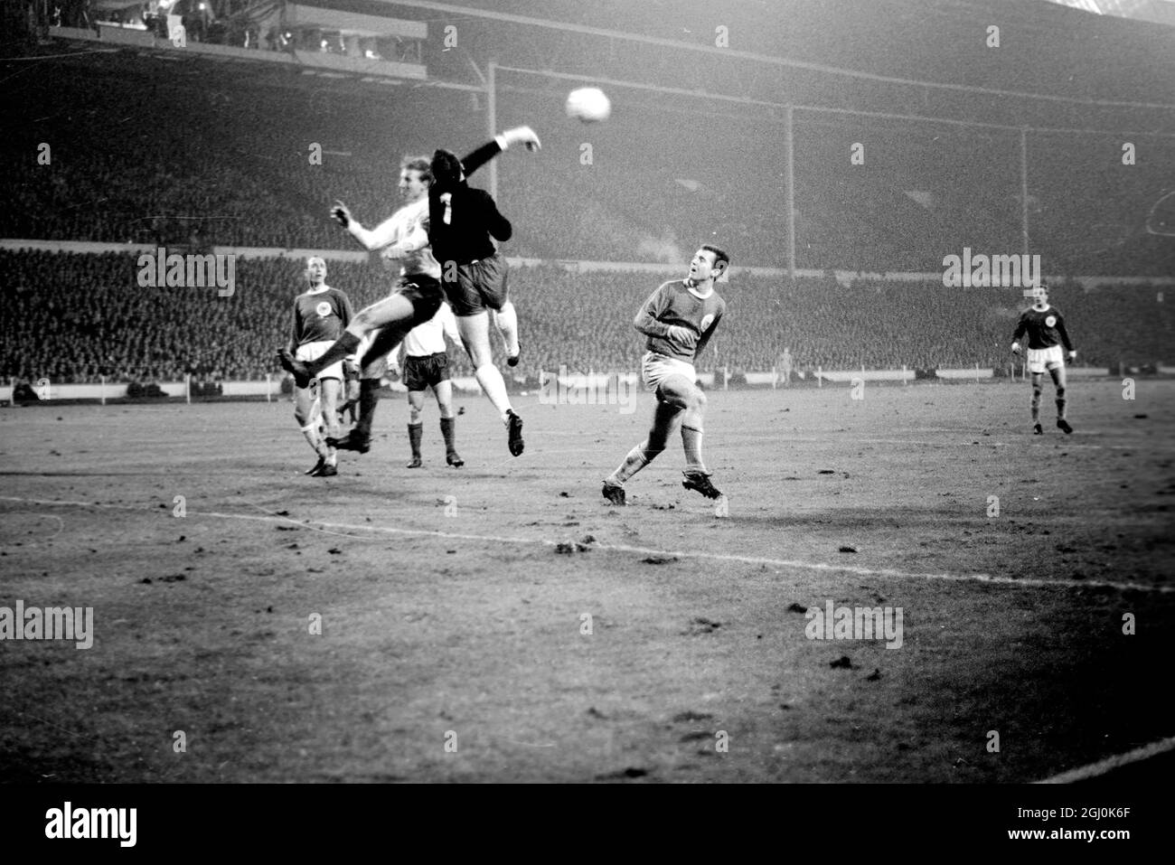 Wembley, Middlesex: England und Leeds United Spieler Jackie Charlton; (Mittelhälfte). Der westdeutsche Torhüter Hans Tilkowski wird heute Abend während des Internationalen Fußballvereins im Empire-Pool zwischen Deutschland und England in Aktion gezeigt. Das Spiel wurde bei starkem Regen und bei schlaffen Bedingungen gespielt; es wurde von einer Menge beobachtet, die auf 50,000 geschätzt wurde. 23. Februar 1966 Stockfoto