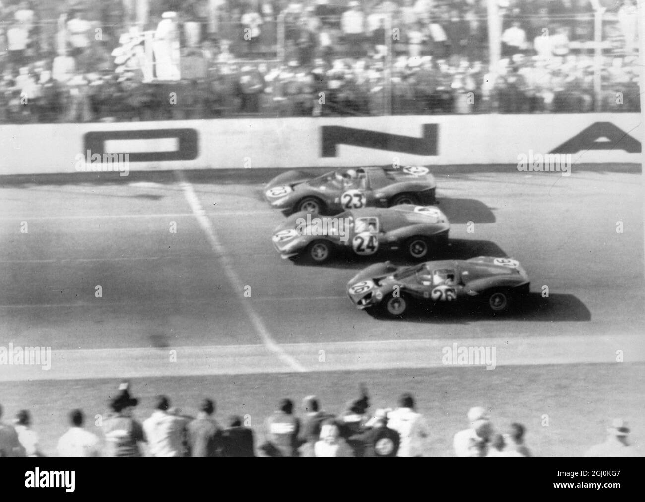 Am 5. März stehen die Zuschauer auf beiden Seiten der Rennstrecke von Dayton Beach, als die siegreichen Ferraris am Ende des 24-Stunden-Continental-Rennens die karierte Flagge zeigen. Das Siegerauto war die No23, die von Lorenzo Bandini, dem Ankermann des Ferrari-Werksteams, gefahren wurde. Nr. 24 ist Ludovico Scarfiotti, wie Bandini, ein Italiener. Am Steuer von 26 Pedro Rodriguez, Mexikos Hauptfahrer. März 1967 5 Februar 1953 Stockfoto